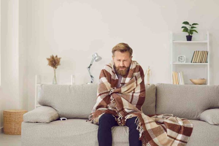 Uomo infreddolito sul divano 