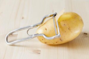 Pelapatate poggiato su patata con buccia