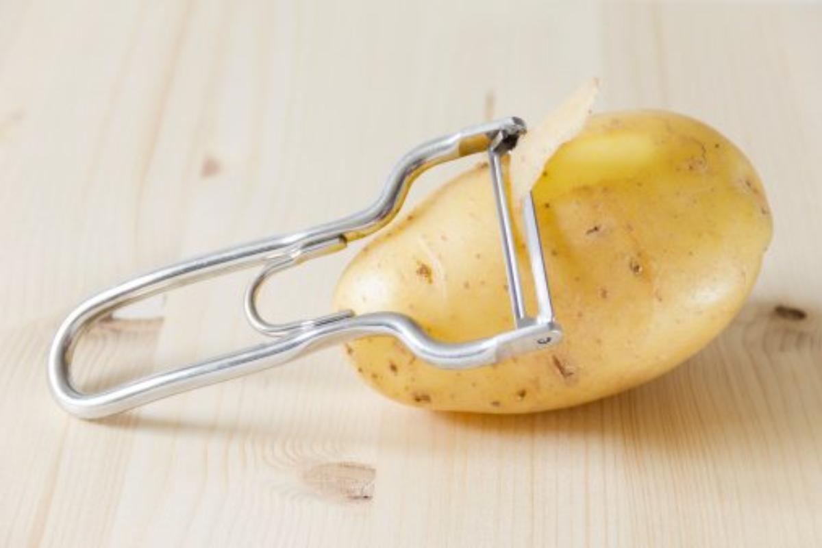 Pelapatate poggiato su patata con buccia