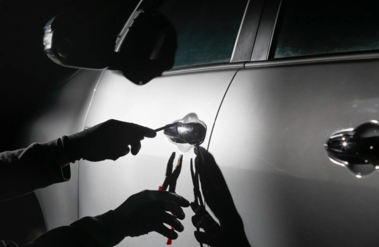 ladro che cerca di forzare la portiera di un'automobile