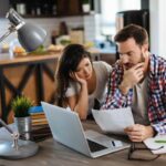 Coppia al PC, foglio in mano, pensierosi