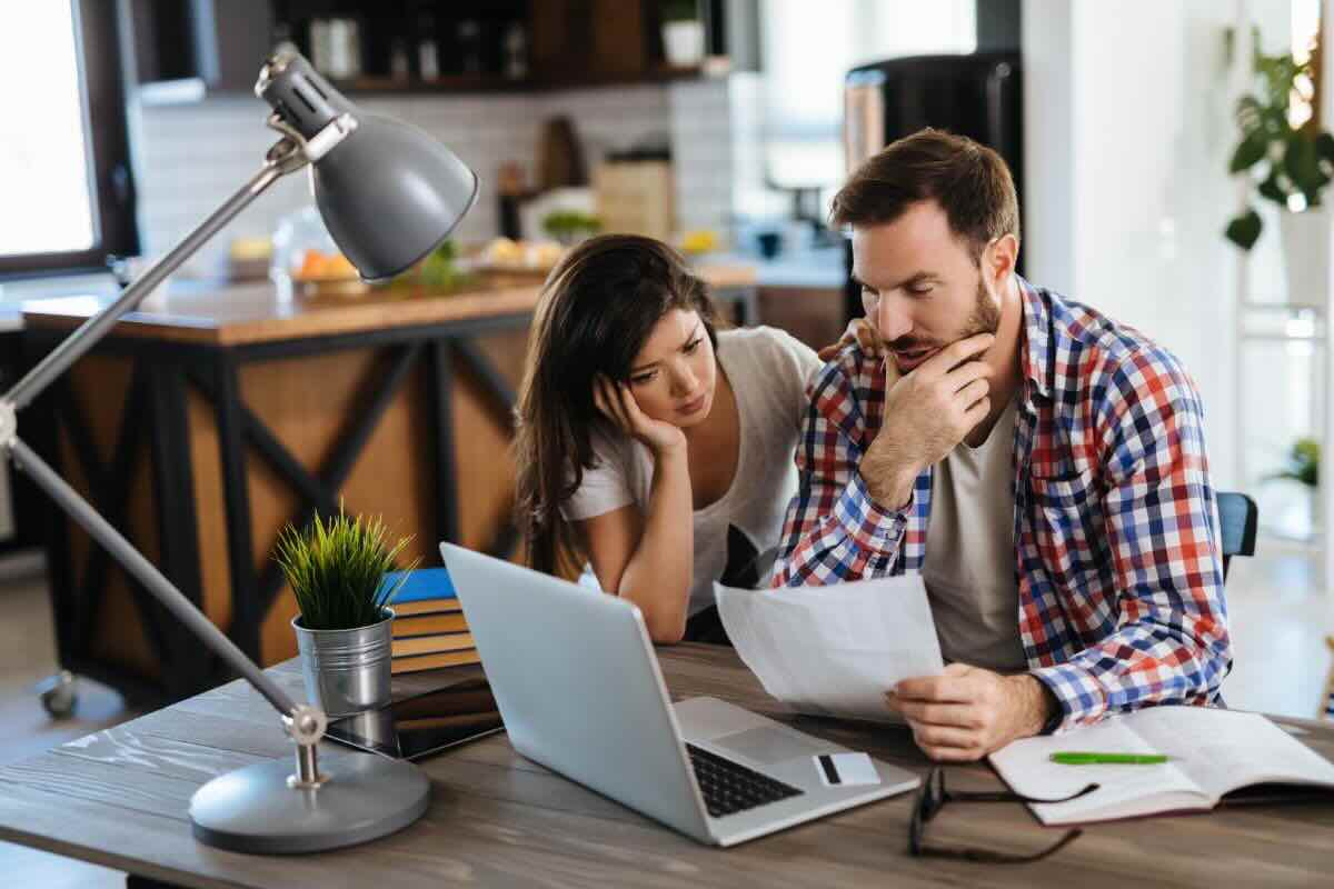 Coppia al PC, foglio in mano, pensierosi