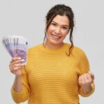 donna sorridente con in mano tante banconote da 500 euro