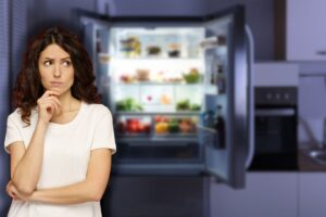 frigorifero aperto e donna che pensa