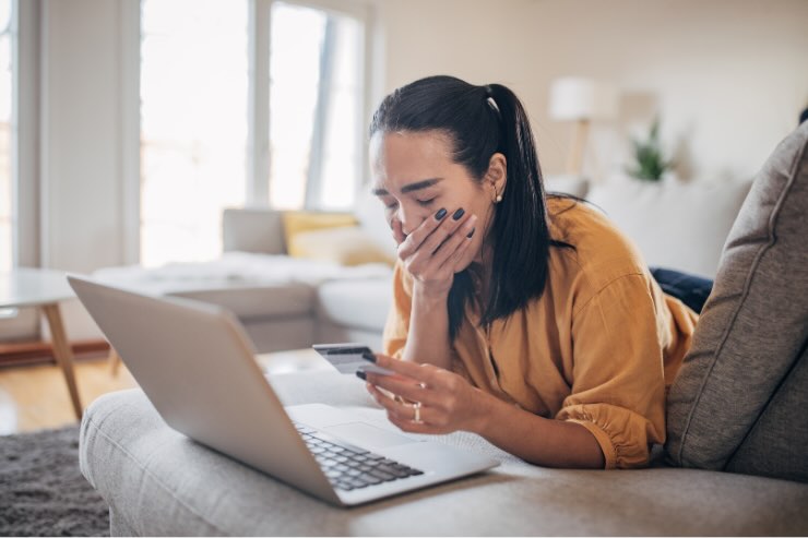 donna triste con carta in mano davanti a pc