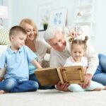 nonno figlia e nipoti a terra a leggere un libro