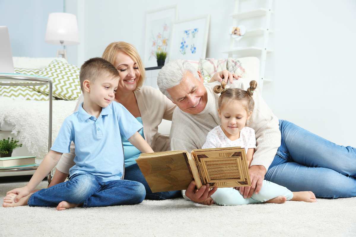 nonno figlia e nipoti a terra a leggere un libro