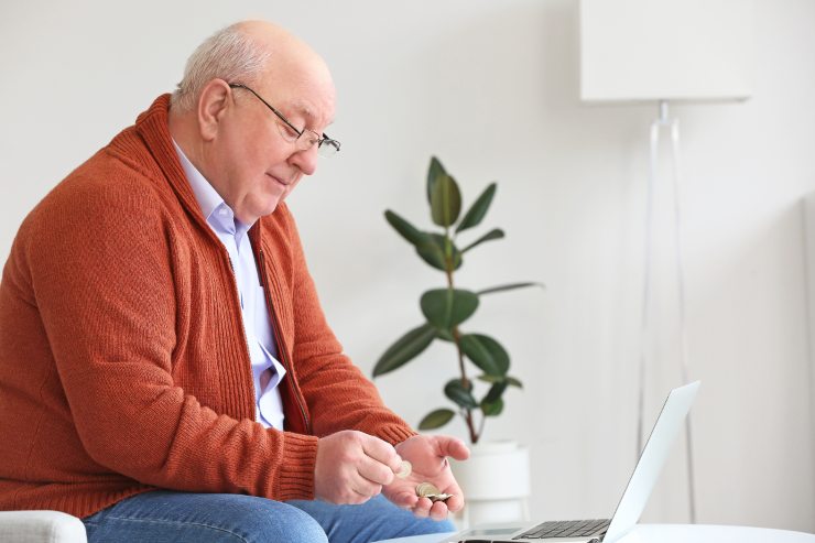 uomo anziano conta le monete che ha in mano