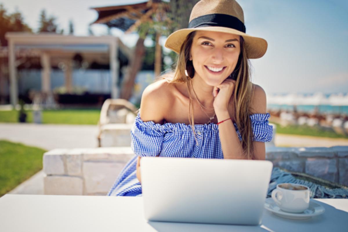 donna sorridente che lavora al computer vicino alla spiaggia
