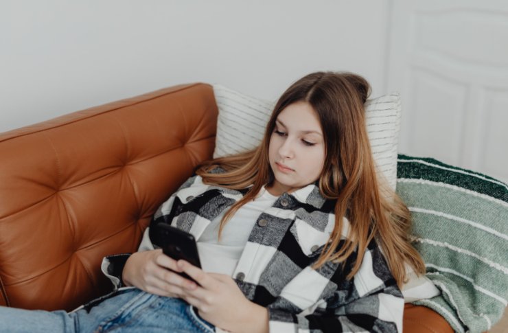 ragazza sdraiata sul divano con il cellulare in mano