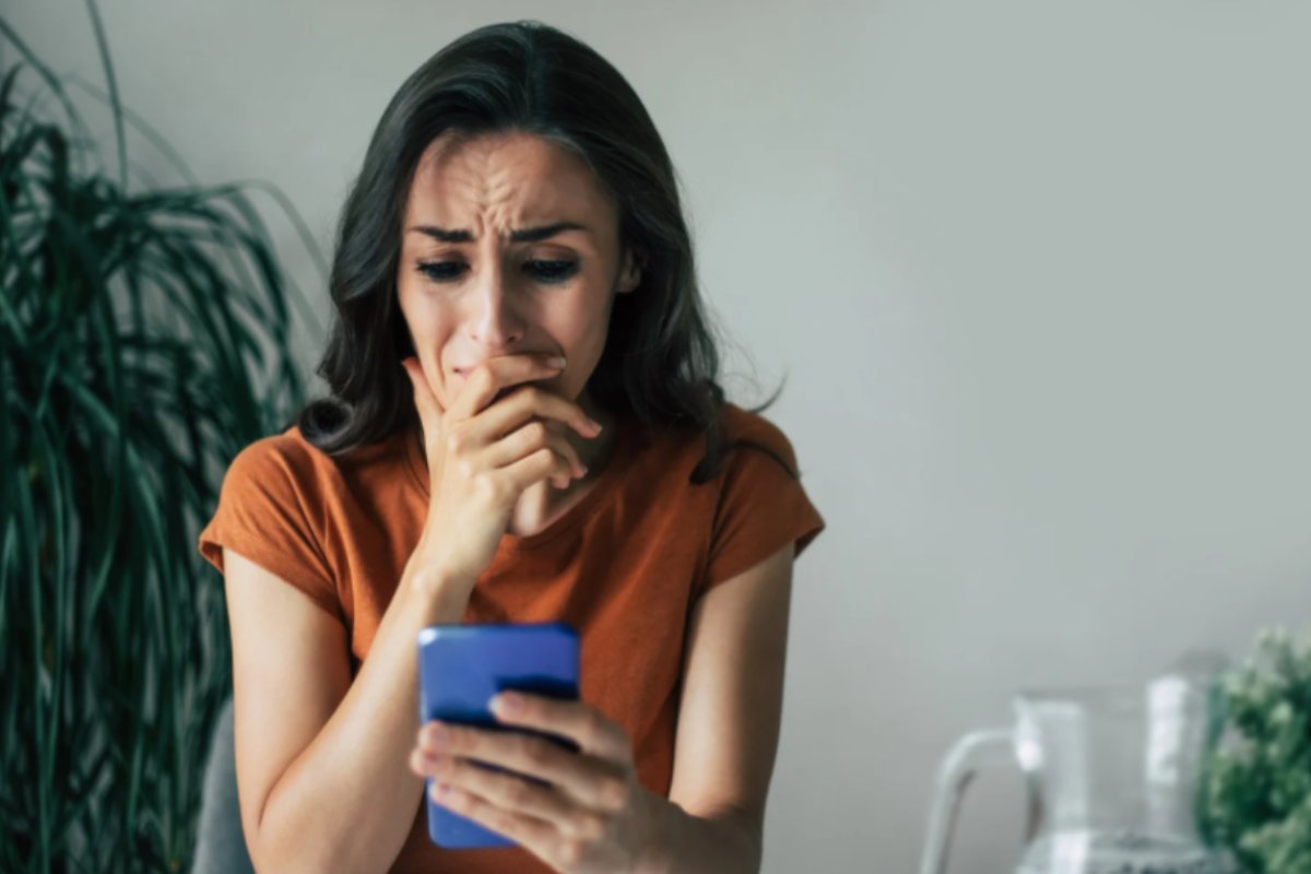donna preoccupata con il cellulare in mano e l'altra mano sulla bocca