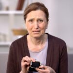 donna anziana che piange con in mano un portamonete vuoto