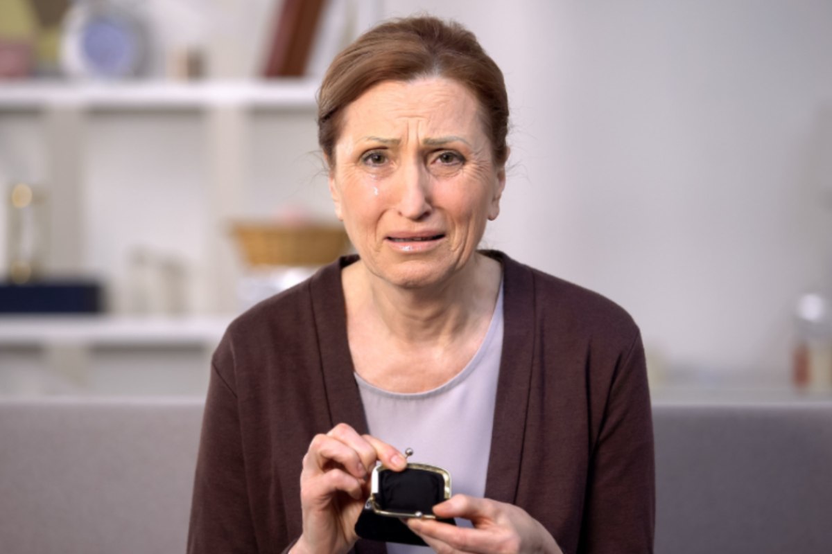 donna anziana che piange con in mano un portamonete vuoto