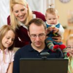 uomo davanti al computer e accanto a lui una donna e tre bambine