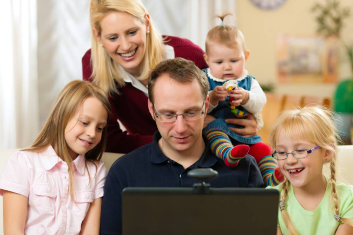 uomo davanti al computer e accanto a lui una donna e tre bambine