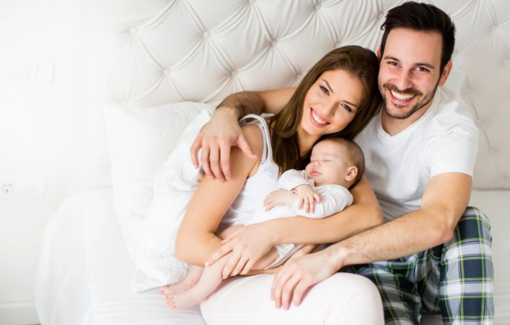 mamma e papà con in braccio un neonato nel letto