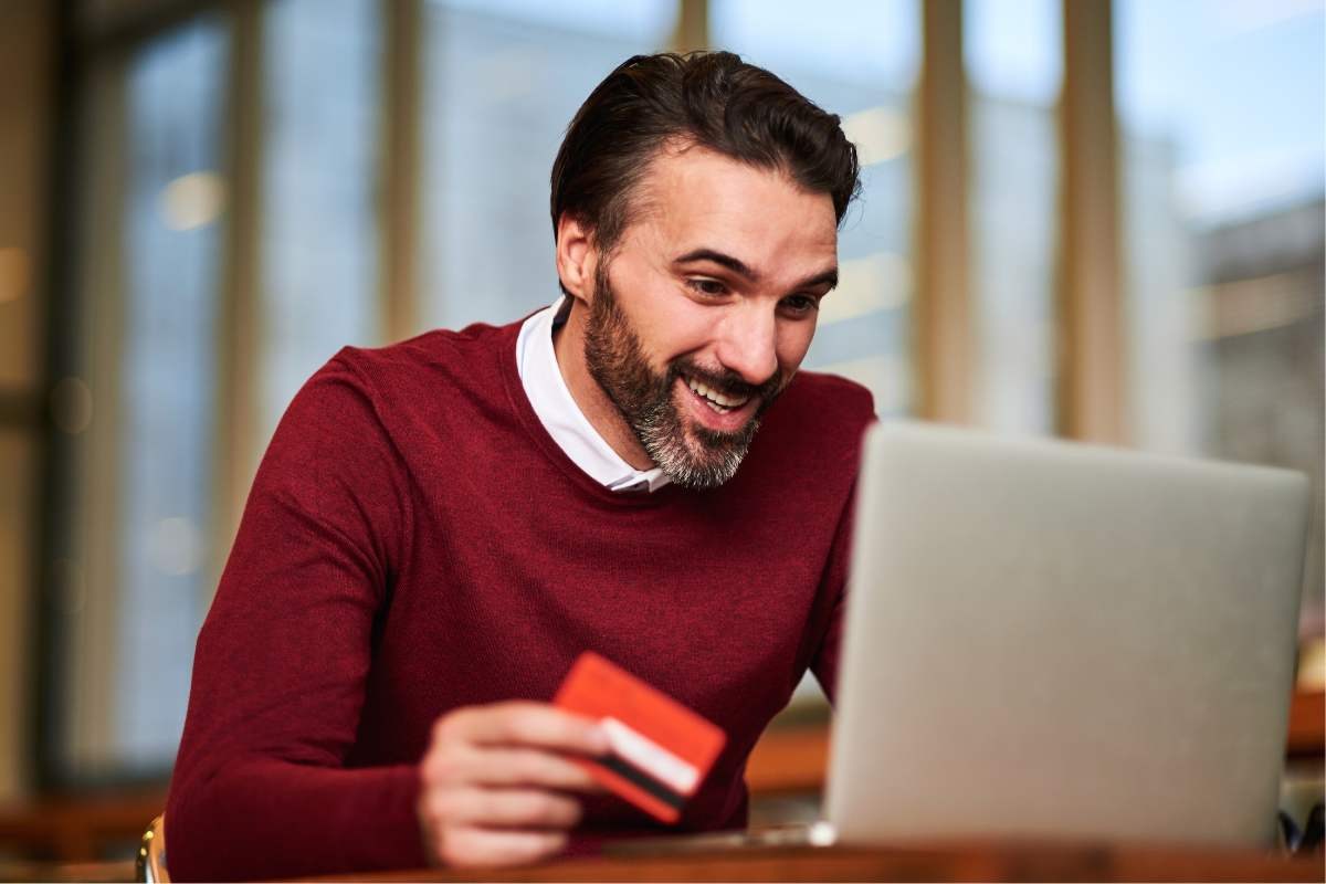 uomo al PC con carta di credito in mano