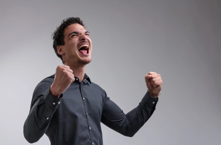 uomo che esulta con la bocca aperta e i pugni chiusi