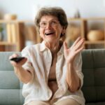 donna seduta sul divano sorridente con il telecomando in mano