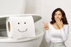 Donna indica carta igienica nel WC con faccina felice disegnata