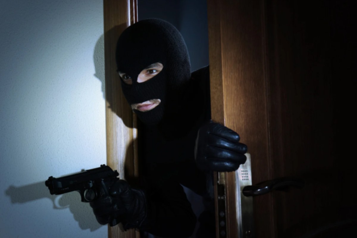 ladro con passamontagna e pistola che entra in casa