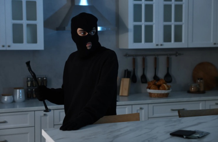 ladro con passamontagna nella cucina di un appartamento