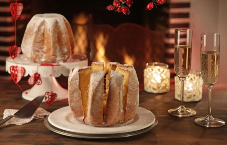 pandoro tagliato a fette e accanto due calici di spumante