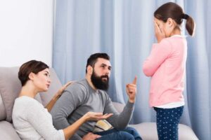 due adulti che litigano con bambina che si copre viso