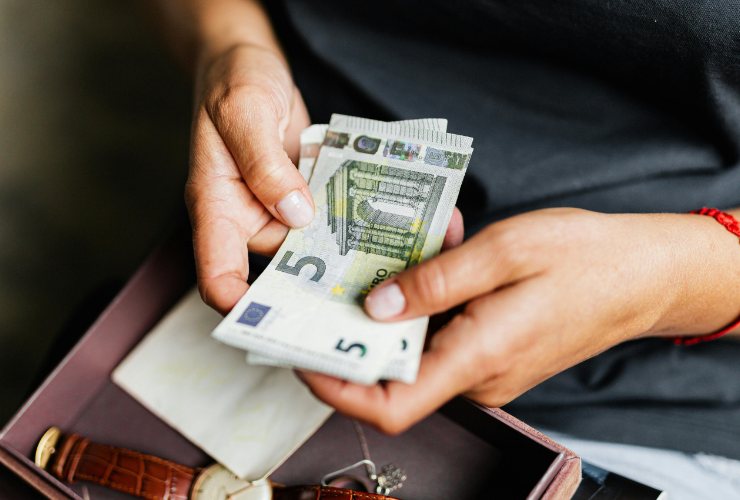 mani che tengono banconote da 5 euro