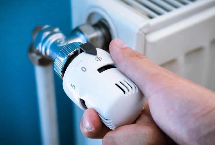 una persona sta girando una valvola termostatica del termosifone